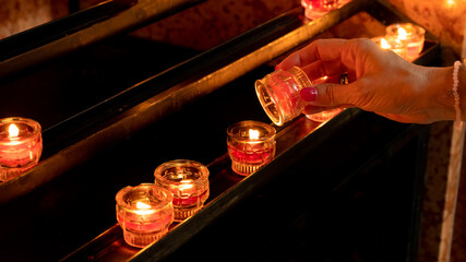 woman lights a candle in a church