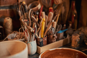 Image of interior potter workshop while different tools standing on wooden table