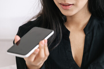 Young business lady listening voice message on smartphone