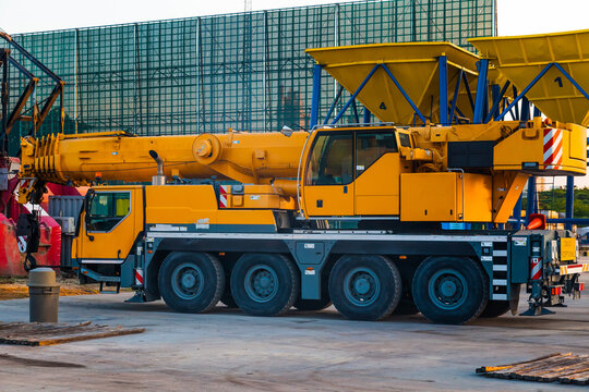 A yellow wheeled truck crane stands in the port of Cartagena, Colombia. Heavy wheeled loading equipment.