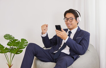 Asian Financial Advisor Wear Headphone and Glasses Smile with Success in Home Office. Businessman Work at Home for Social Distance or Home Quarantine in Covid 19 or Coronavirus Situation