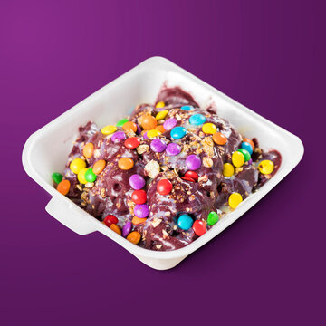 Brazilian Frozen Açai Berry With Condensed Milk, Granola And Confetti On A Styrofoam Lunch Box Ready To Go. Isolated On Purple Background