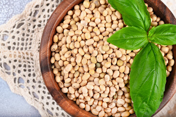 Soybeans in wooden bowl on light background