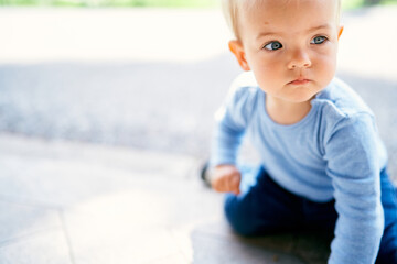 Little girl sits on her knees on the tile. Close-up. Portrait