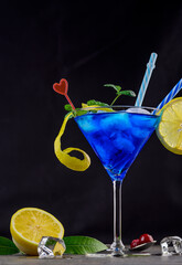 Blue lagoon cocktail with blue curacao liqueur, vodka, lemon juice and soda. Blue cocktail in martini glasses on black background