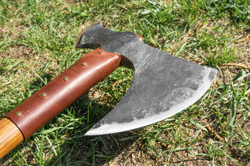 the battle ax is on the ground next to a large stone. forged ax