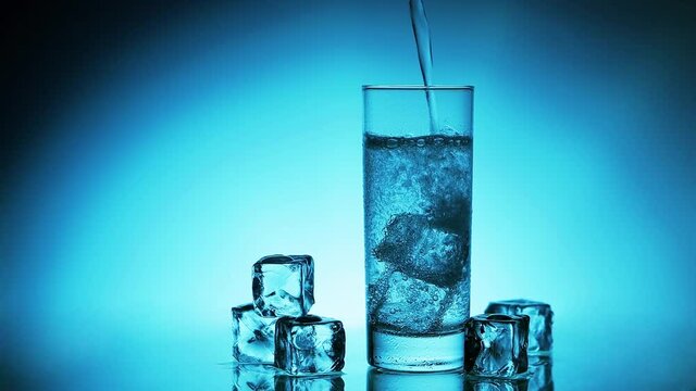 Mineralwasser in einen Eisw&uuml;rfel Glass giessen