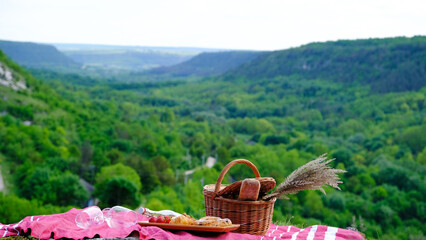 Delicious fresh croissants, baguette, strawberry and wine outside at picnic. Romantic picnic with mountains background.
