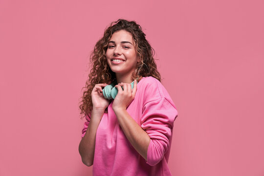 Smiling woman with headphones on pink background