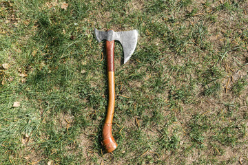 the battle ax is on the ground next to a large stone. forged ax