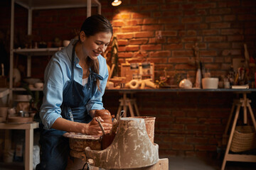 Charming laughing craft woman at the process of manufacturing ceramic product in art studio