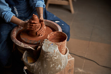 Beautiful elegant ceramicist in apron modeling tableware in pottery workshop