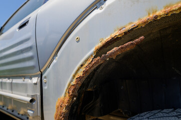 Close-up of rusty wheel arches on a silver car. automobile corrosion and the effect of road chemicals on the condition of the car body