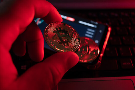 close-up on bitcoin coin with red lighting alluding to falling coin, very short depth of field.