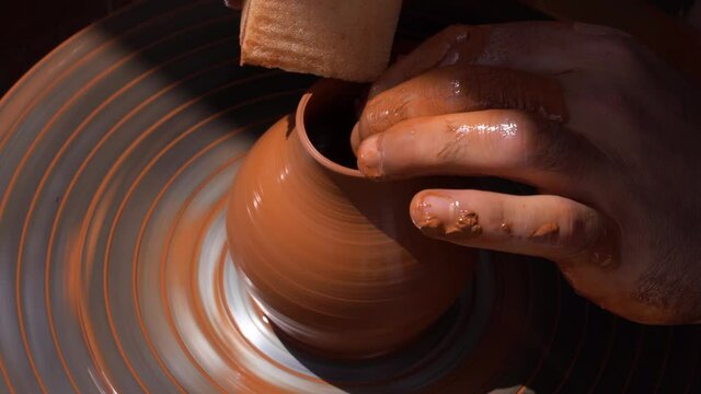 Potter at work. Top view man's hands making ceramic pot on the  wheel. The sculptor makes jug out of clay closeup. Handmade pots. Creativity and traditional crafts concept
