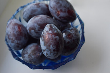 Fresh plum. Autumn harvest. Blue plums in a blue glass dish.close-up view from above.