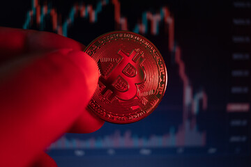 close-up on bitcoin coin with red lighting alluding to falling coin, very short depth of field. - Powered by Adobe