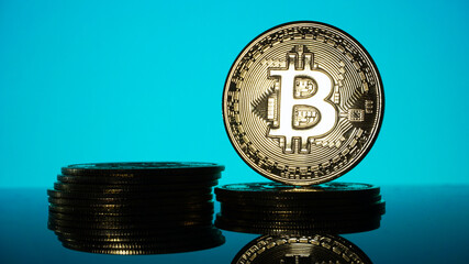 Gold Bitcoins on blur cyan background. Conceptual image for worldwide cryptocurrency and digital payment system.