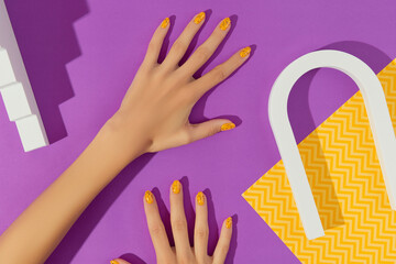 Manicured womans with trendy nail design on purple background