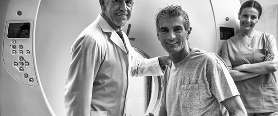 Man in 40s ready to undergo MRI scan, assisted by two smiling doctors