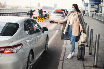 Stylish woman in medical mask taking cab at airport © Svitlana