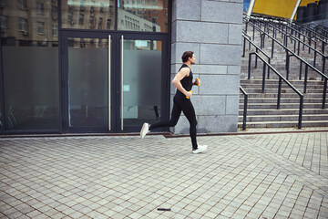 Young sportsman running near the city stadium