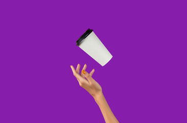 Fototapeta na wymiar Womans hand with flying paper cup on purple background. Takeaway food and drink