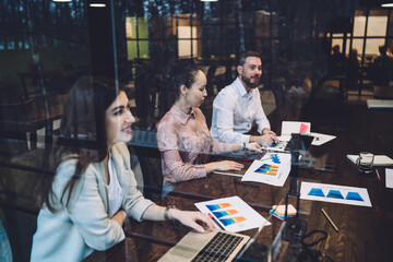 Young cheerful people discussing diagrams in conference hall