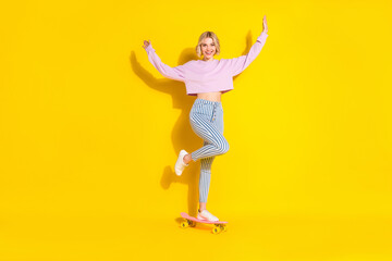 Fototapeta na wymiar Full length body size view of attractive cheerful girl riding skate having fun isolated over bright yellow color background