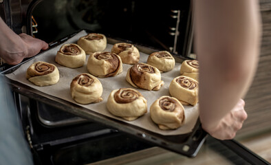 Preparation of cinnamon rolls. A woman puts buns of buns on a baking tray.