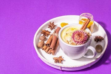 Golden turmeric milk with ice on bright yellow background