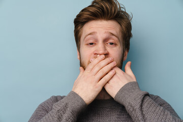 White ginger man with beard covering his mouth and looking at camera