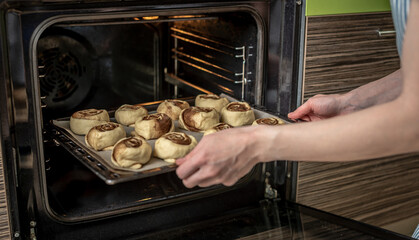 Preparation of cinnamon rolls. A woman puts buns of buns on a baking tray.