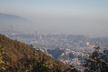 Naklejka premium A mountain with a city in the background -- Una montaña con una ciudad de fondo