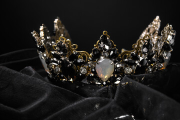 Beautiful crown with black and opal stones on a black background, close-up