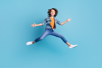 Fototapeta na wymiar Full length photo of young excited boy happy positive smile jump show hands isolated over blue color background
