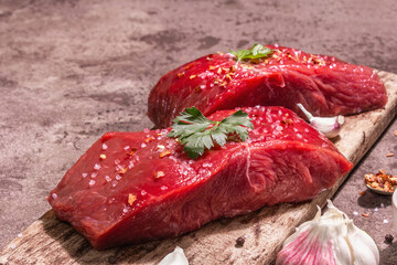 Raw beef steaks on a wooden cutting board