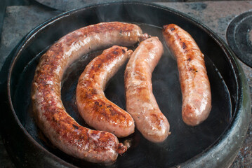 Roasted sausages prepared in earthen clay pot on rural outside oven