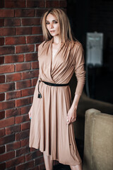 A beautiful girl in an evening dress on the background of a dark stone wall.