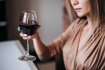 A woman holds a glass of red wine in a restaurant.