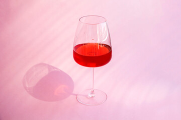 Still life with red refreshing summer alcoholic cocktail drink with strawberry in wine glass on pink background. Fruit or berry wine. Minimalism.