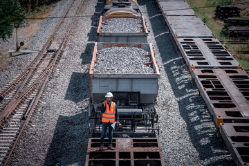 Taken photo from above, railroad engineers inspect railroad tracks and stone-carrying convoys for industrial, he used radio communication and document on hand control work.
