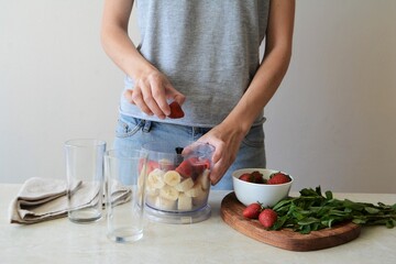 Woman cooking a strawberry and banana smoothie. Healthy food concept