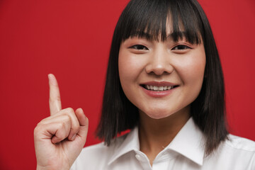 Young asian woman wearing shirt smiling and pointing finger upward