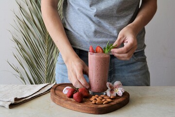 Woman holds a glass of strawberry smoothie. Healthy food concept