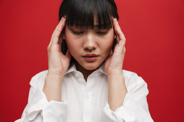 Young asian woman wearing shirt with headache rubbing her temples