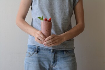 Woman holds a glass of strawberry smoothie. Healthy food concept