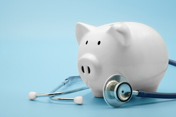 Piggy bank with stethoscope isolated on light blue background with copy space. Health care financial checkup or saving for medical insurance costs concept. - obrazy, fototapety, plakaty