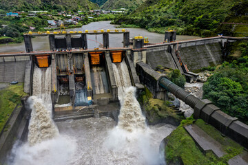 Aerial front view over a large hydroelectric dam of which water is getting through the gates after a heavy rainfall