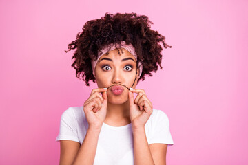 Photo portrait of funny girl showing fake mustache fooling isolated on pastel pink color background